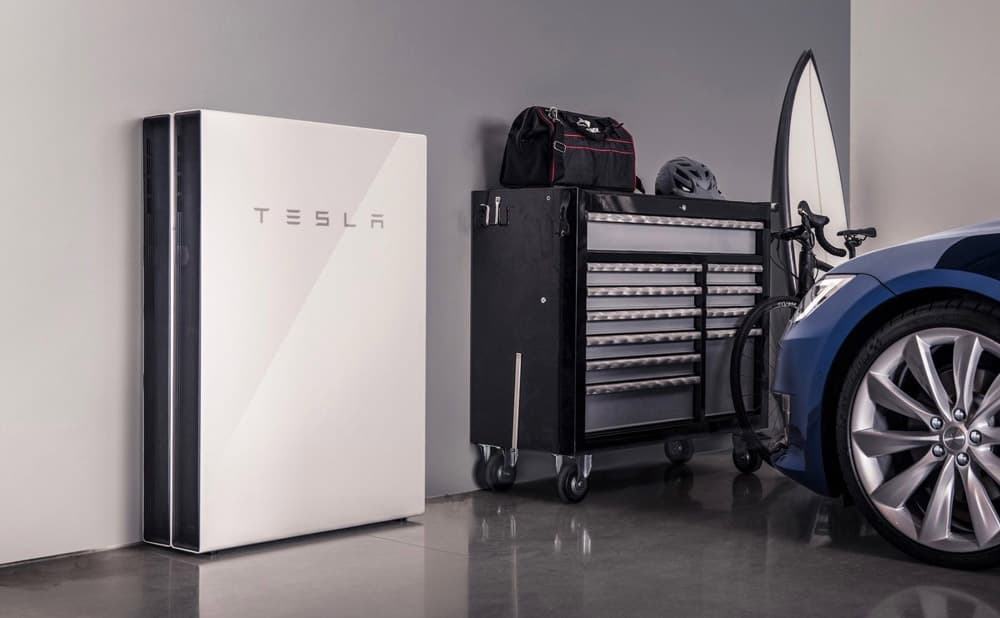Tesla Powerwall installed in a garage, alongside an electric car.