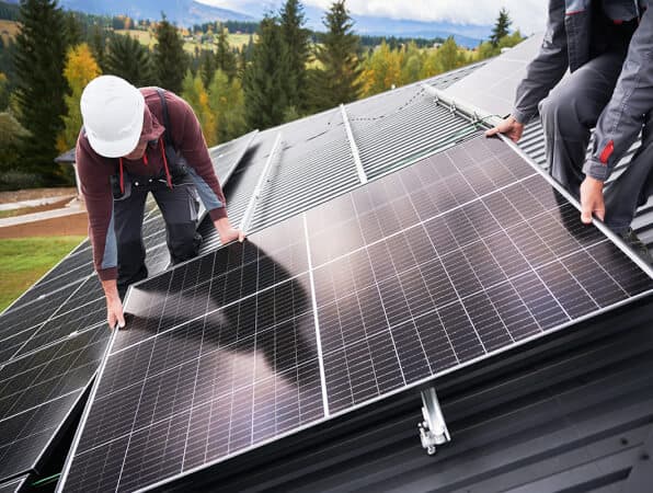 Solar installers wearing safety gear, installing solar on a rooftop.